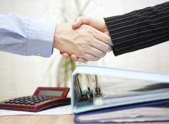 businessman and businesswoman are handshaking over binders